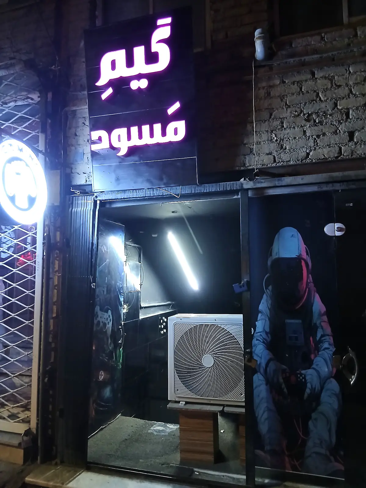 ورودی گیم مسعود در شب، با تابلوی نئونی «گیم مسعود»